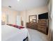Bright bedroom with white linens, wooden dresser, and television; light tile floor at 1192 Via Galuppi St, Kissimmee, FL 34759