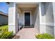 Welcoming front porch with a dark-colored front door, brick flooring, and a seating area at 1192 Via Galuppi St, Kissimmee, FL 34759