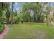 View of lush backyard with mature trees, landscaping, and a brick pathway, perfect for outdoor enjoyment at 5881 Avenue H, Mc Intosh, FL 32664