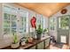 Sunroom filled with natural light, showcasing vintage details, wood flooring, and large windows overlooking the yard at 5881 Avenue H, Mc Intosh, FL 32664