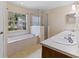 A bathroom featuring dual sinks, a soaking tub, and a walk-in shower at 9879 Sw 38Th Ave, Ocala, FL 34476