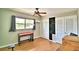 A bedroom featuring wood-look flooring, a ceiling fan, a window with gray curtains, and neutral-colored walls at 103 13Th Se St, Winter Haven, FL 33880