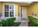 Inviting front entrance with white door, lush landscaping, and yellow textured walls providing warmth and curb appeal at 3017 Mission Lakes Dr, Lakeland, FL 33803