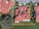 Stunning aerial view of a home with a red tile roof, skylights, a screened in lanai, and a pond in the back at 2680 Clubhouse Dr, Lake Wales, FL 33898