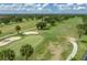 Aerial view showcasing a well-maintained golf course with palm trees and verdant green grass on a sunny day at 2680 Clubhouse Dr, Lake Wales, FL 33898