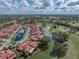 Scenic aerial view of a community with homes with red tile roofs near a golf course, lake, and community pool at 2680 Clubhouse Dr, Lake Wales, FL 33898