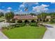 Attractive clubhouse features an American flag, tile roof, covered entry, and manicured lawn with beautiful tropical trees at 2680 Clubhouse Dr, Lake Wales, FL 33898