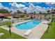 Outdoor community pool featuring lounge chairs, tropical landscaping, and red tile roofs on nearby neighborhood homes at 2680 Clubhouse Dr, Lake Wales, FL 33898