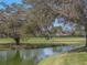 Scenic pond with a golf cart in the background, framed by lush trees and greenery on a sunny day at 2680 Clubhouse Dr, Lake Wales, FL 33898