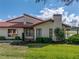 Home's exterior features a tile roof, lush landscaping, and a serene view of the adjacent pond at 2680 Clubhouse Dr, Lake Wales, FL 33898