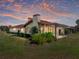 Inviting home exterior features a tile roof, lush landscaping, and a serene outdoor patio area at sunset at 2680 Clubhouse Dr, Lake Wales, FL 33898