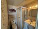 Modest bathroom with floral wallpaper, glass-enclosed shower, toilet, vanity with sink, and small storage shelves at 1893 N Lake Reedy Blvd, Frostproof, FL 33843