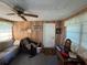 Living room featuring wood paneling, ceiling fan, and furniture, with a window for natural light and a door at 1893 N Lake Reedy Blvd, Frostproof, FL 33843