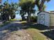 A utility shed is located next to the water and a gravel driveway on a property filled with mature palm trees at 1893 N Lake Reedy Blvd, Frostproof, FL 33843