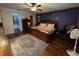 Spacious main bedroom with blue accent wall, wood floors, fan and access to the walk-in closet at 2134 R E Byrd Rd, Frostproof, FL 33843