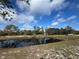 Picturesque view of a pond surrounded by lush trees reflecting the blue sky and fluffy clouds at 2134 R E Byrd Rd, Frostproof, FL 33843