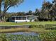 Charming single-story home featuring a screened porch and manicured lawn, overlooking a tranquil waterfront at 2263 Lake Reedy N Blvd, Frostproof, FL 33843