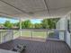 A covered porch with a wood deck and white railing that overlooks the backyard and green space at 2391 Buck Board Trl, Lake Wales, FL 33898