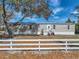 Exterior view of a home with a metal roof, white fence, and a small front yard at 2391 Buck Board Trl, Lake Wales, FL 33898