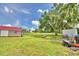 A sprawling backyard featuring a tool shed, a red roofed shed, and a riding lawn mower at 301 S Clinch Lake Blvd, Frostproof, FL 33843
