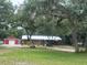 Charming single-story brick home featuring mature landscaping, a metal roof, and a detached two-car garage at 3123 Mar Lisa Cove Rd, Lake Wales, FL 33898