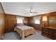 Bedroom featuring wood paneling, two windows, and a ceiling fan at 450 Westfall Dr, Kenansville, FL 34739