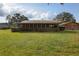 Ranch-style home with a metal roof and screened porch, surrounded by a green lawn and mature trees at 450 Westfall Dr, Kenansville, FL 34739