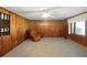 Living room featuring wood paneled walls, carpeted flooring, and a comfortable armchair at 450 Westfall Dr, Kenansville, FL 34739