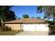 Two-car garage with white doors and decorative windows set in brick house with brown roof and blue sky at 9 Silver Sand Rd, Frostproof, FL 33843