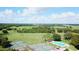 Aerial shot of a community featuring tennis courts, a pool, and a golf course with lush greenery at 1077 Medinah Way, Winter Haven, FL 33884