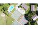 A captivating aerial view of community tennis courts, a pool, and buildings surrounded by mature trees and lush green space at 1077 Medinah Way, Winter Haven, FL 33884