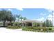 Exterior view of a clubhouse featuring tropical landscaping and a covered entrance at 1077 Medinah Way, Winter Haven, FL 33884