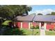 Inviting home featuring a metal roof, well-maintained lawn and a charming red fence for added privacy at 1077 Medinah Way, Winter Haven, FL 33884