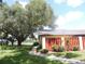 Charming exterior view showcasing a well-manicured lawn, mature trees, and a paved walkway at 1077 Medinah Way, Winter Haven, FL 33884