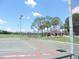 Outdoor tennis courts adjacent to a green lawn area with a sheltered seating area, all surrounded by fencing at 1077 Medinah Way, Winter Haven, FL 33884
