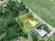 An aerial view showcases a property with two structures and a spacious yard bordered by dense, verdant trees at 111 D St, Frostproof, FL 33843