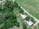 Property aerial view featuring a house with a spacious yard and surrounding lush greenery, adjacent to a paved road at 111 D St, Frostproof, FL 33843