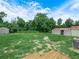 The property has a expansive backyard with grass, sandy spots, sheds, and trees at 111 D St, Frostproof, FL 33843