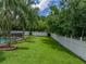 Expansive backyard featuring a white fence, lush lawn, pool, and palm trees at 1144 Cephia St, Lake Wales, FL 33853