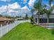 Wide shot of the verdant backyard with a white fence, pool and palm trees at 1144 Cephia St, Lake Wales, FL 33853