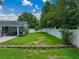 Manicured backyard with a white fence, garden and covered patio with grill at 1144 Cephia St, Lake Wales, FL 33853
