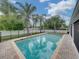 A beautiful swimming pool featuring brick pavers, surrounded by tall palm trees, with a white fence around the perimeter at 1144 Cephia St, Lake Wales, FL 33853