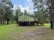 Back exterior view of the home with a large yard surrounded by trees at 1885 Pfundstein Rd, Babson Park, FL 33827