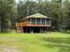 Elevated home with a screened-in porch, complemented by a lush green lawn and natural landscape at 1885 Pfundstein Rd, Babson Park, FL 33827