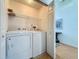 Functional laundry room with a washer, dryer, shelving, and adjacent hallway with wood floors at 2200 Mallory Cir, Haines City, FL 33844