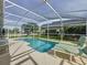 Sparkling pool with screened enclosure with lounge seating and green landscaping at 2200 Mallory Cir, Haines City, FL 33844