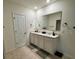 Dual sink bathroom vanity with a large mirror and neutral tile flooring at 2655 Swooping Sparrow Dr, Harmony, FL 34773