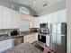 Updated kitchen with stainless steel appliances, granite countertops, and white cabinets at 2696 Hemingway Ave, Haines City, FL 33844