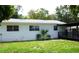 Backyard view of the house with a covered patio, well-maintained lawn, and mature trees at 302 S Palm Ave, Frostproof, FL 33843