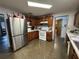 Well-lit kitchen featuring a stainless-steel refrigerator, white appliances, and wood cabinets at 400 W 4Th Ct, Frostproof, FL 33843